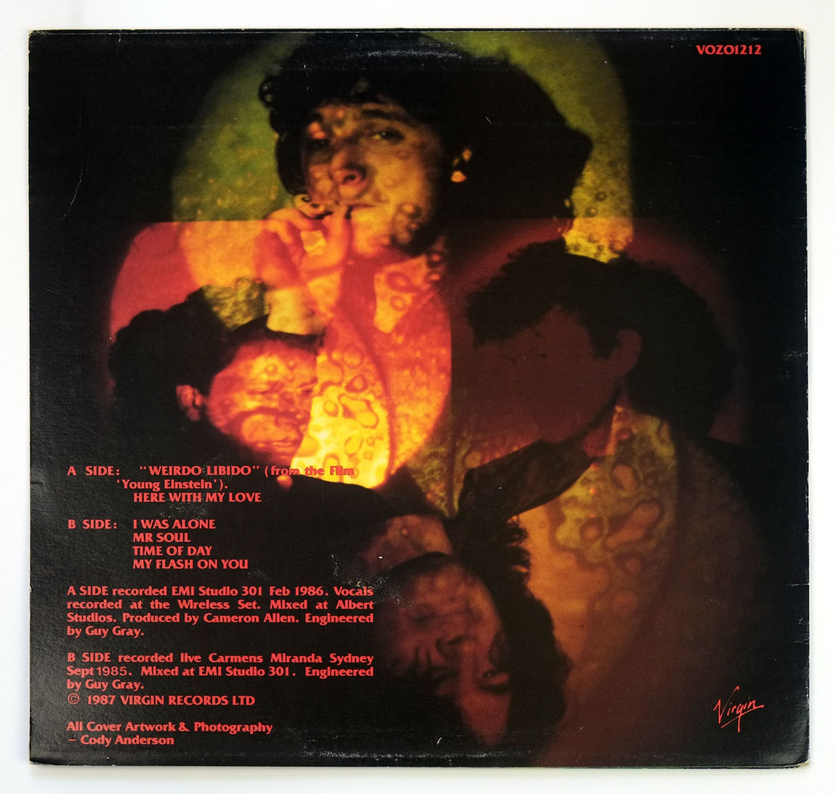 Back cover of Lime Spiders' 'Weirdo Libido' (1987). A psychedelic collage of overlaid, semi-transparent band member faces bathed in red and yellow hues. A central figure smokes a cigarette, while distorted, ghostly images of other members fade in and out of the textured background. Tracklist and production credits appear in bold red text at the bottom.